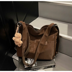 Detail view of coffee brown nylon tote bag with plush bear charm and spacious front pocket