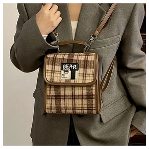 Détail du sac bandoulière vintage à carreaux marron avec garniture en cuir et ours