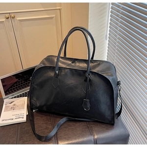 Gros plan du sac de voyage en cuir noir avec poignées et bandoulière amovible