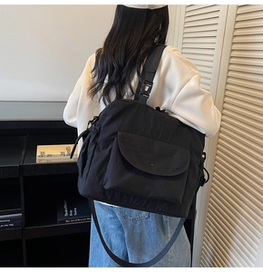 Detail of black large nylon tote bag with drawstring pockets and wide shoulder straps