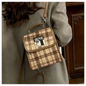 Détail d'un sac à dos vintage en tweed écossais marron avec écusson ours mignon