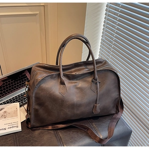 Détail d'un sac de voyage en similicuir marron avec une large bandoulière tissée élégante