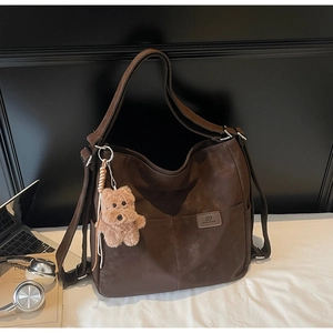 Detail of dark brown suede tote bag with exterior pocket and cute plush bear charm