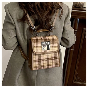 Détail d'un mini sac à dos à carreaux vintage avec badge ours et sangle en cuir sur modèle