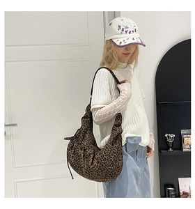 Detailed view of leopard print crescent bag with drawstring bow and textured fabric
