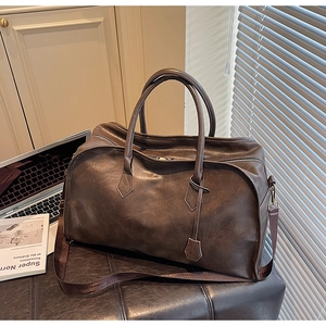 Détail d'un sac de voyage vintage en cuir marron foncé avec poignées et bandoulière