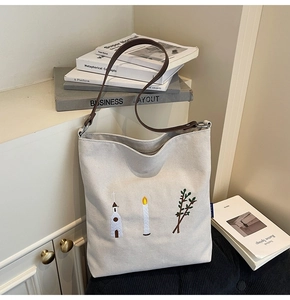 Close-up of intricate church embroidery on a white canvas tote bag with brown leather straps