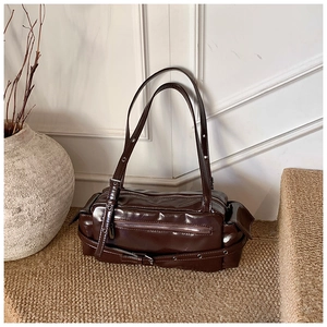 Detail view of glossy chocolate brown shoulder bag with silver metal eyelets and side pocket