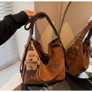 Detail of brown canvas hobo bag with adjustable strap and cute plush bear charm