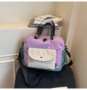 Detail of color-block nylon crossbody bag featuring front pocket and woven strap detail