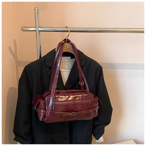 Detailed close-up of dark red glossy bowling bag with adjustable buckles and metal zippers