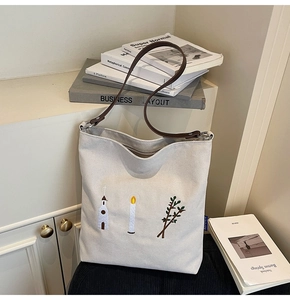 Detail shot of vintage embroidery on off-white canvas tote bag with leather strap