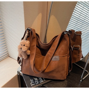 Detail of vintage brown tote bag with suede texture, side pocket, and teddy bear charm