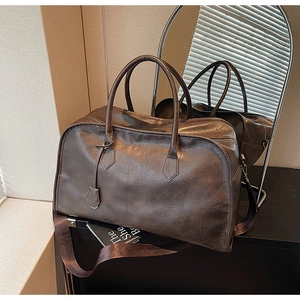 Détail d'un sac de voyage en similicuir marron avec bandoulière et texture vintage