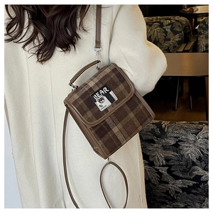 Détail du sac à carreaux avec bandoulière en cuir marron et écusson Bear Design