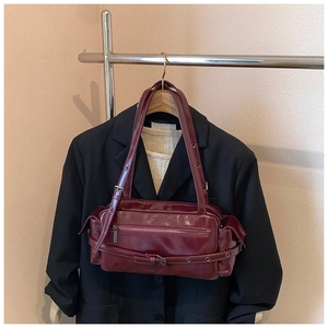 Close-up of retro wine red shoulder bag with silver buckles on a garment hanger