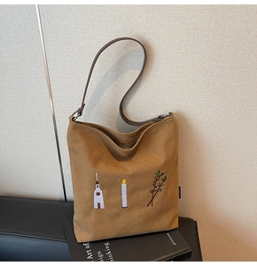 Detail of vintage embroidery on a brown canvas hobo bag featuring botanical patterns