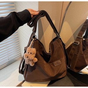 Detail view of coffee brown tote bag with suede texture and plush dog charm accessory