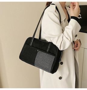 Detailed view of black rhinestone shoulder bag with silver studs on a white trench coat