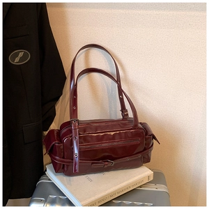 Detail of burgundy glossy leather shoulder bag with silver hardware and utility pockets