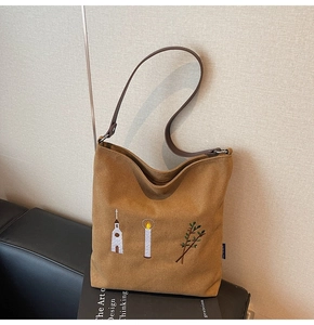 Detail of vintage embroidery and suede texture on a brown large capacity tote bag