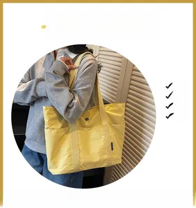 Detail of a bright yellow tote bag showing the wide shoulder straps and side label
