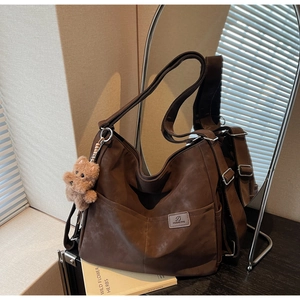 Detail of vintage brown tote bag with plush bear charm and textured synthetic leather