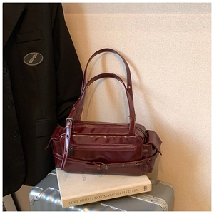 Detail view of burgundy patent leather Boston bag with retro buckles in a fashion setting