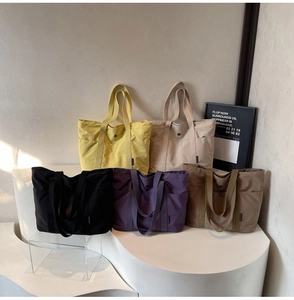 Detail showing five colors of large capacity tote bags with side pockets and webbing handles