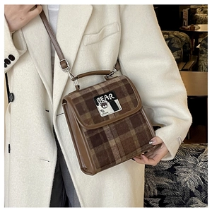 Détail du sac cabas à carreaux avec bordure en cuir marron et écusson ours sur laine