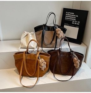 Close-up of large suede tote bags with leather trim and cute teddy bear pendants