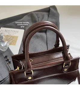 Detail of round handles and gold hardware on a vintage dark brown oil wax leather bag
