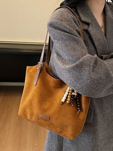 Grand sac cabas en daim caramel avec pendentif perlé porté avec un blazer gris