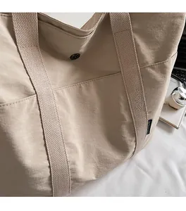 Detailed close-up of beige nylon tote bag with side pocket and magnetic buckle