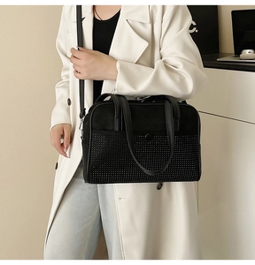 Detail of black rhinestone shoulder bag with silver studs and knot handle on model