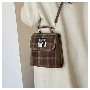 Détail d'un sac bandoulière à carreaux marron avec écusson ours sur tweed et cuir