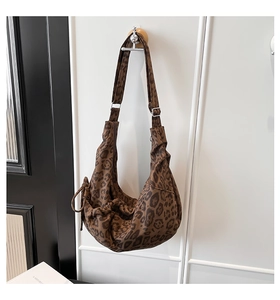 Detail of leopard print hobo bag with drawstring knots and adjustable strap on wall