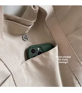 Macro detail of beige tote bag with functional front pocket and CM metal logo