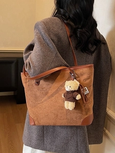 Large caramel suede tote bag with bear star patterns and plush bear charm on model