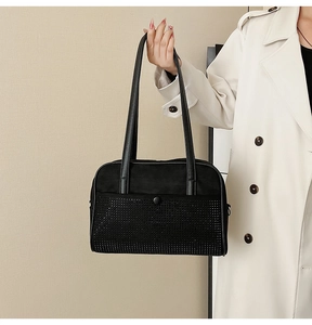 Close-up of black suede shoulder bag with shimmering rhinestones and leather straps