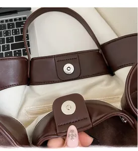 Macro detail of dark brown leather handbag with magnetic closure and canvas lining
