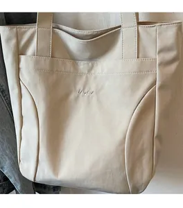 Detail of cream tote bag with Midolat embroidery and front pocket for organization