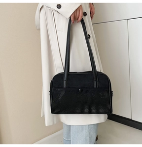 Close-up of black rhinestone knot shoulder bag featuring matte leather and studded texture
