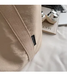 Close-up of beige tote bag with black logo tag, nylon texture, and daily essentials