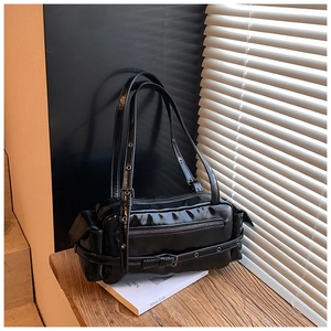 Detail view of black patent leather underarm bag with metal eyelets and side pockets
