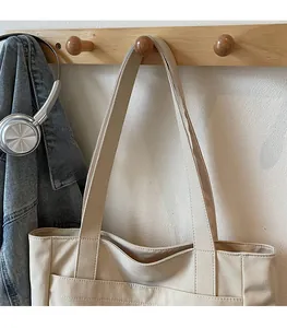 Detail of beige canvas tote bag with comfortable straps hanging in a lifestyle setting