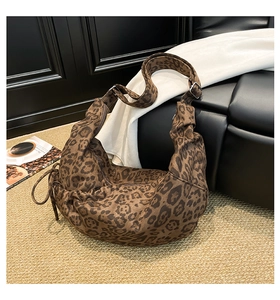 Detail of the leopard print hobo bag with adjustable strap and drawstring on a sofa