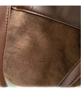 Detailed close-up of soft brown suede material and smooth leather trim on tote bag