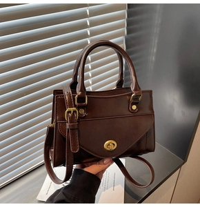 Detail of dark brown vintage faux leather satchel with golden twist lock and adjustable strap
