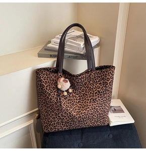 Détail d'un grand sac cabas à motif léopard avec anses brunes et breloque chaton en peluche
